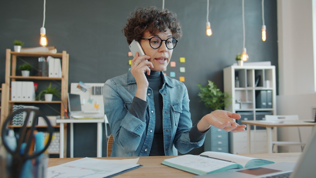 Ejecutiva intentando contactar por teléfono, con gesto de frustración.